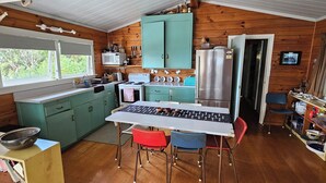 A compact kitchen with teal cabinets, a white stove, and a stainless steel refrigerator. - Beachfront Property in Private Bay with only 12 houses and private beach access. (Matapouri)