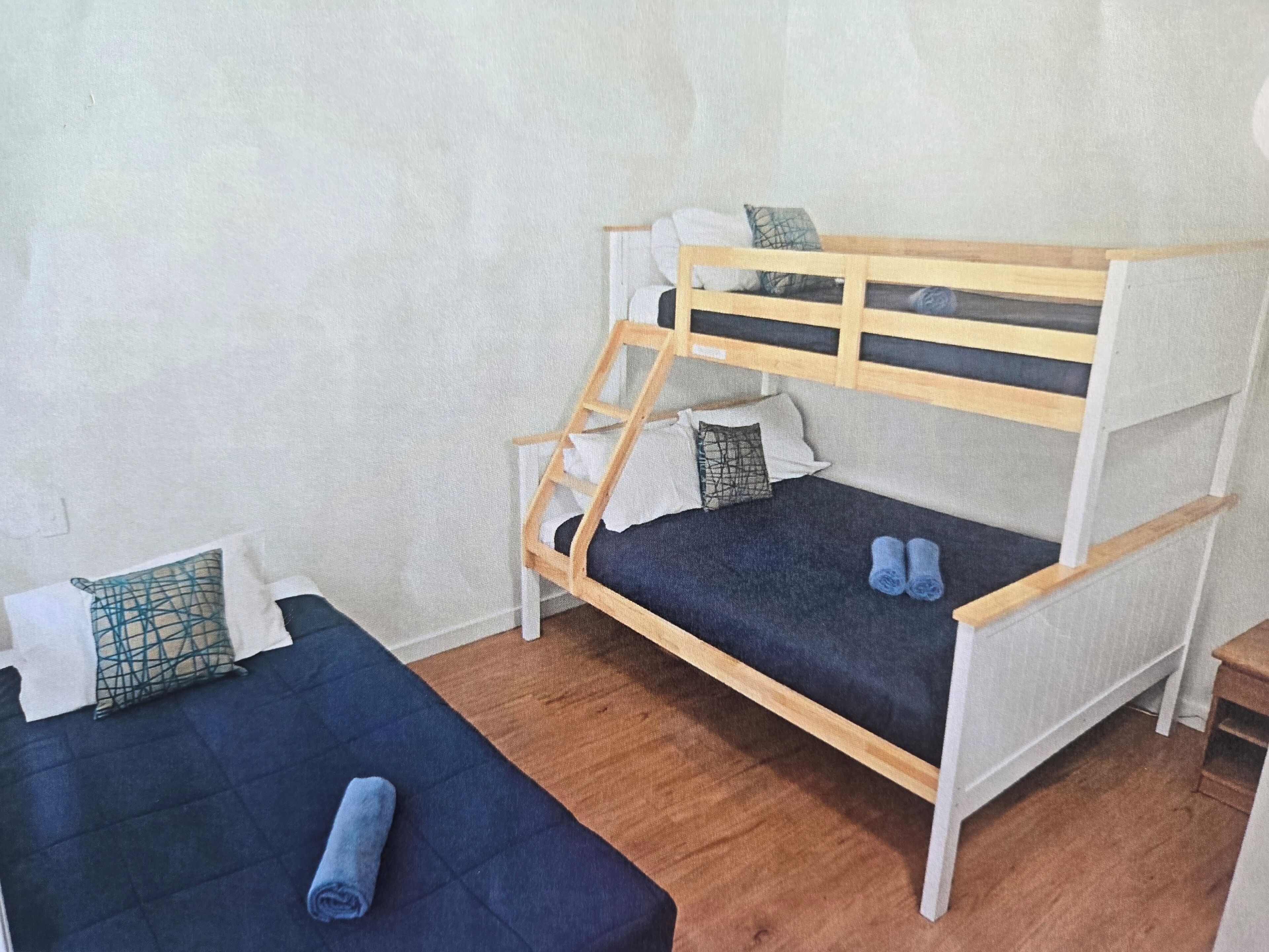 Une chambre avec deux lits superposés, dont l’un est muni d’une échelle en bois, et une petite table.