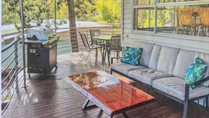 Un espace extérieur abrité, aménagé avec une table en bois, un canapé et un barbecue.