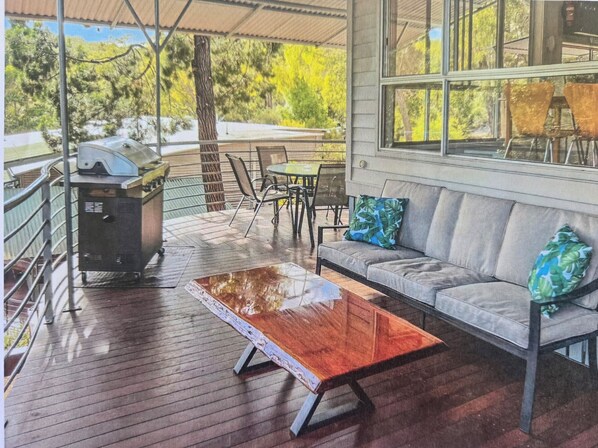 Un espacio de estar al aire libre cubierto con una mesa de madera, un sofá y una parrilla.