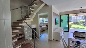 Un interior moderno con una escalera, una zona de comedor y vistas al exterior.