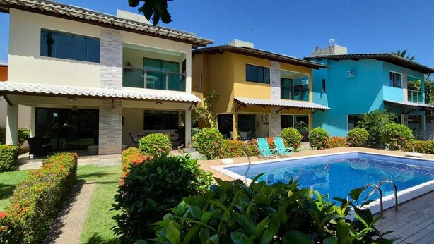 Un moderno complejo residencial con piscina, jardines bien cuidados y varias casas con balcones.