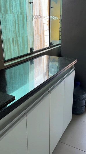 Eine Küche mit Glasrückwand, weißen Schränken und einer schwarzen Arbeitsplatte.