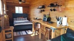 L’intérieur chaleureux d’un chalet avec un lit, une table à manger en bois et un coin cuisine.