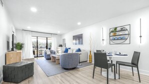 Een moderne woonkamer met een bank, stoelen, een salontafel en een eethoek met een tafel en stoelen.