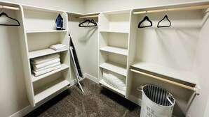 Un armario ropero con estantes blancos, una barra para colgar y una cesta de ropa.