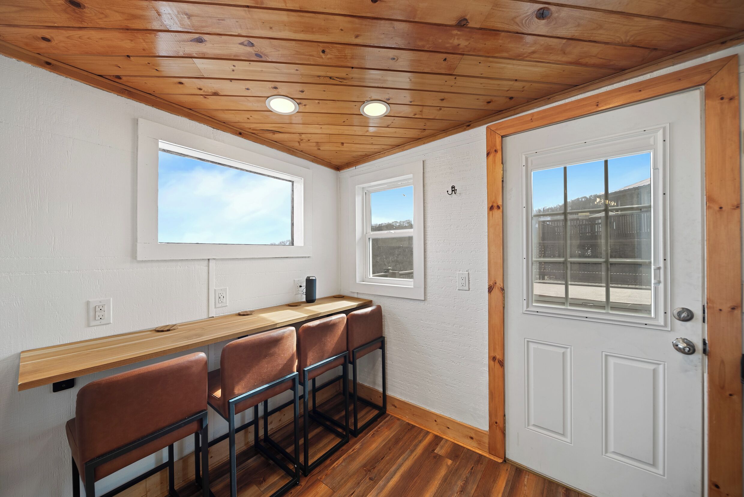 Une pièce avec un plafond en bois, une porte blanche et une fenêtre donnant sur un immeuble.