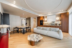 A modern living room with a sofa, coffee table, and dining area. - Lakeside Luxe Apartment 2BR Prime Location (Tirana)