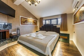 A modern hotel room with a large bed, a fireplace, a painting, and a view of the city. - Miracle No 8 Central Modern Duplex (Tirana)