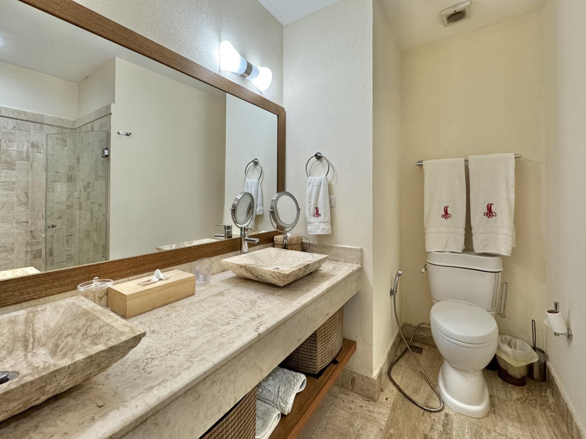 A bathroom with a marble sink, a large mirror, a toilet, and a shower area.