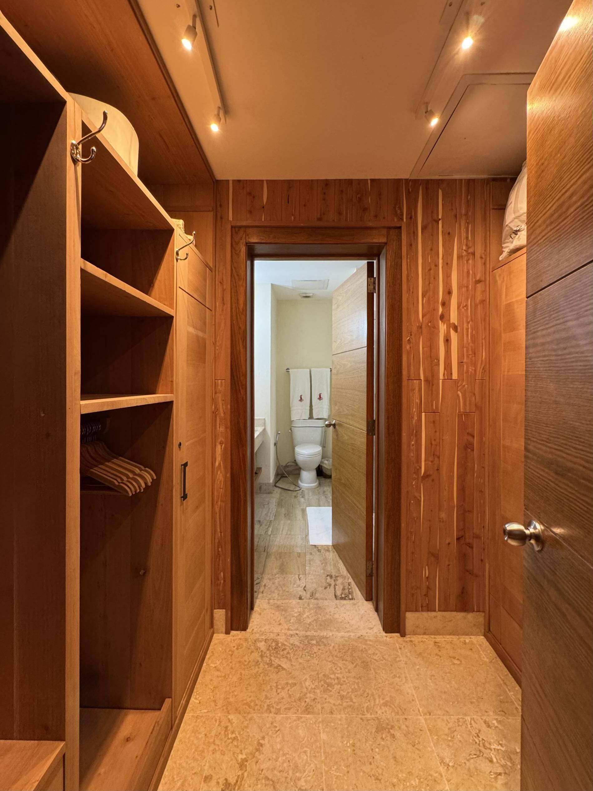 A wooden hallway leading to a bathroom with a toilet and towel rack.