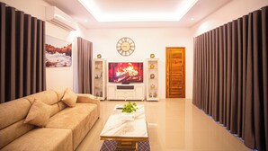 Un salon moderne comprenant un canapé, une table basse, un téléviseur et un ventilateur de plafond.