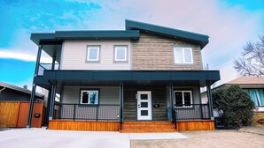 A two-story residential building with a balcony, a front porch, and a visible front door.
