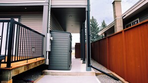 A residential building with a covered porch, a wooden deck, and a metal fence.