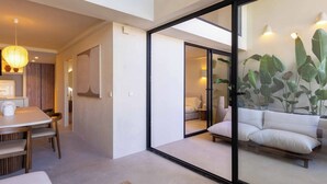 Um interior moderno com área de refeições, uma porta de vidro deslizante que dá para um quarto e uma planta grande.