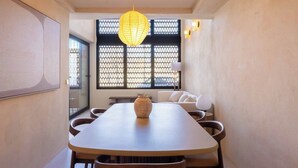 Uma sala de jantar moderna com uma mesa comprida, cadeiras, um vaso e uma luminária pendente decorativa.