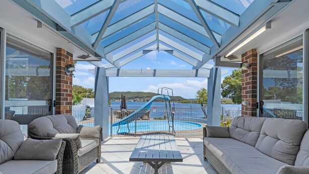 Ett takförsett utomhusområde med en pool, solstolar och utsikt över havet.