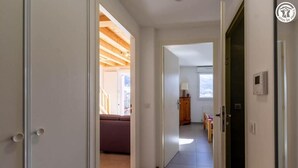 Un pasillo con un sofá y una lámpara al fondo, que conduce a una habitación con ventana.