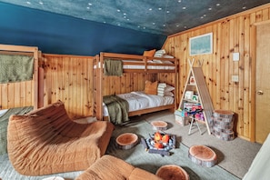 Une pièce chaleureuse avec un lit superposé, un plancher en bois, un petit foyer et un tipi.