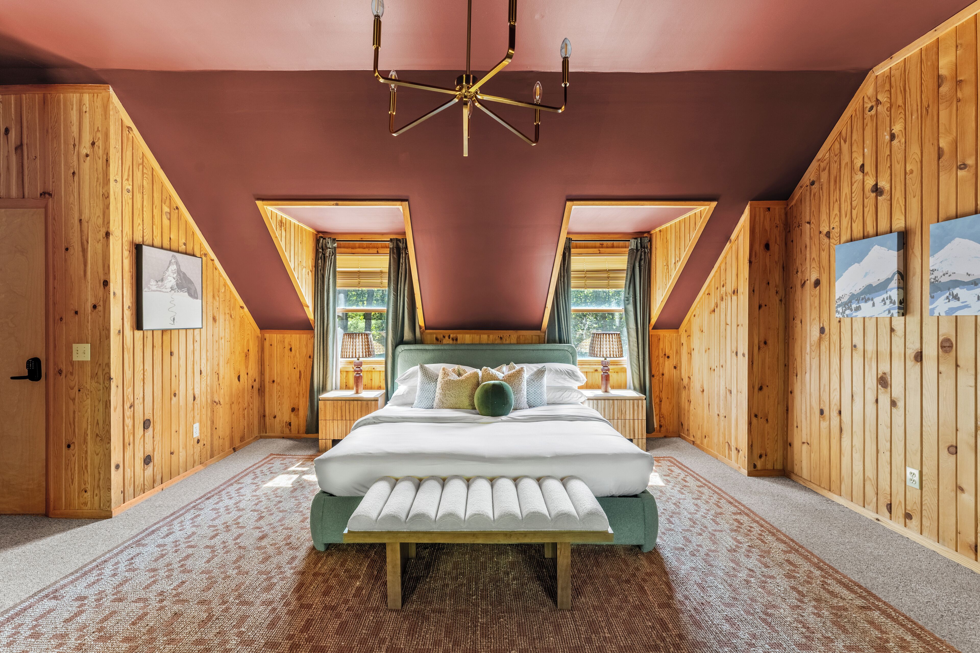 A bedroom with a large bed, wooden walls, and a sloped ceiling.