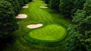 Un campo de golf con búnkeres de arena y árboles frondosos.