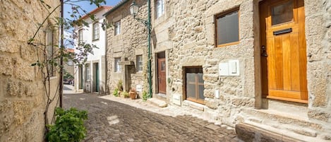 Una estrecha calle adoquinada bordeada por edificios de piedra con puertas y ventanas de madera.