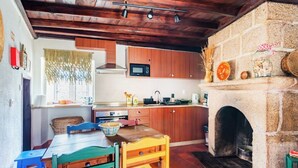 Una cocina rústica con armarios de madera, una chimenea de piedra y un comedor con una mesa y sillas de madera.