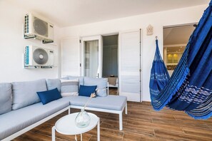 Ein modernes Wohnzimmer mit einem grauen Sofa, einem weißen Couchtisch und einer blauen Hängematte.