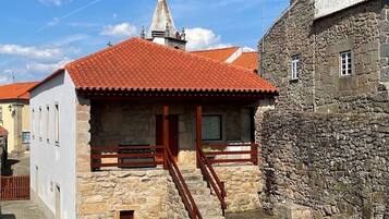 Un bâtiment en pierre avec un toit recouvert de tuiles rouges, un escalier en bois et une petite fenêtre.