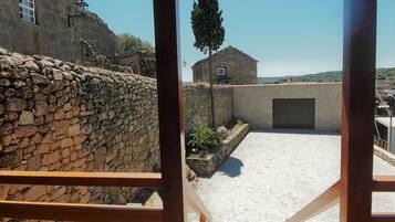 Un mur de pierre, un petit bâtiment avec une porte et un ciel dégagé.
