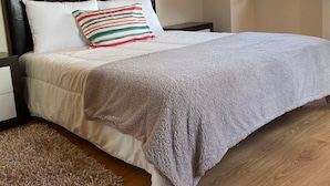 Un dormitorio con una cama, una mesita de noche, una ventana y suelo de madera.
