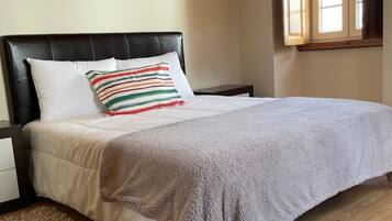 Une chambre à coucher avec un lit, une table de chevet, une fenêtre et un plancher en bois.
