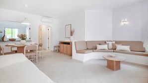 A modern living room with a sofa, a dining table, and a coffee table. - Clube Albufeira - 2BR Pool, Kids Club & Family Fun (Albufeira)