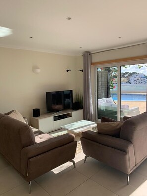Ein modernes Wohnzimmer mit Fernseher, Glastisch und zwei Sofas.