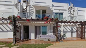 Un bâtiment moderne à deux étages, doté d’un patio couvert, d’un escalier et offrant une vue sur la mer.