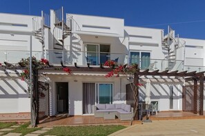 Ein modernes, zweistöckiges Gebäude mit einer überdachten Terrasse, einer Treppe und Blick aufs Meer.