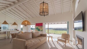 Un salón amplio con sofá, sillas, una mesa de comedor y un gran ventanal con vistas al exterior.
