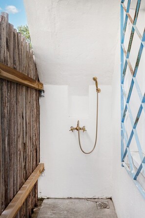 Ein kleiner, abgeschlossener Duschbereich mit Holzlattenzaun und einer blauen Fliesenwand.