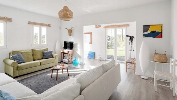 Ein modernes Wohnzimmer mit einer Couch, einem Couchtisch, einem Fernseher und einem großen Fenster.