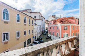 Eine schmale Straße mit Häusern an beiden Seiten, einer Fußgängerbrücke und geparkten Autos.