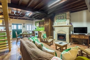 A cozy living room with a fireplace, wooden furniture, and a television.