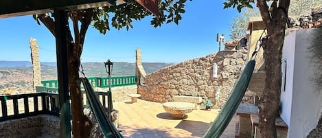 Una hamaca bajo un árbol, un muro de piedra y vistas del paisaje.