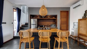 A modern kitchen with a central island, wooden chairs, and a hanging light fixture. - 2 Zen Bali Villa Canggu (Canggu)