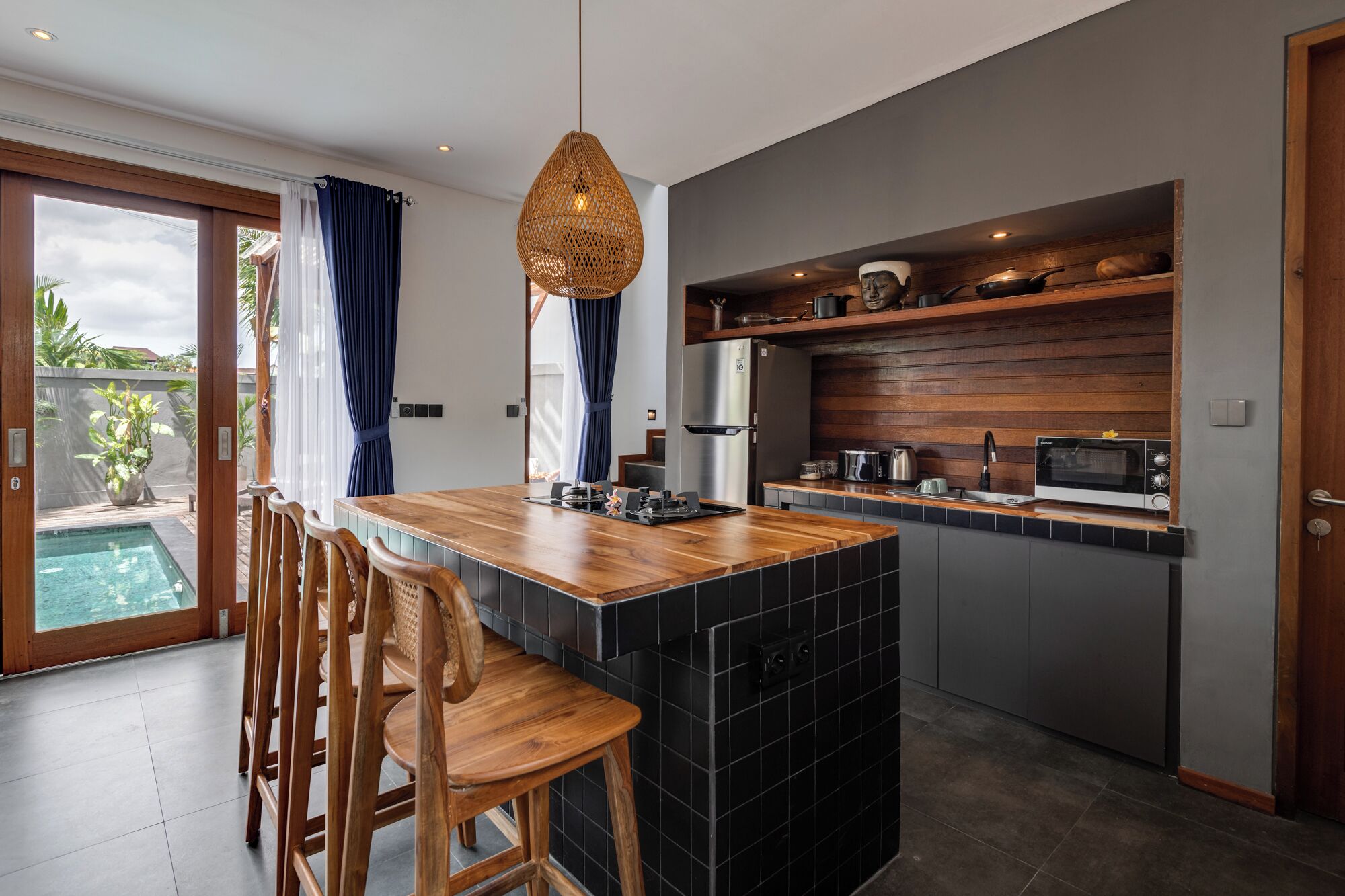 Une cuisine moderne avec un îlot central en bois, des carreaux noirs et un four encastré.
