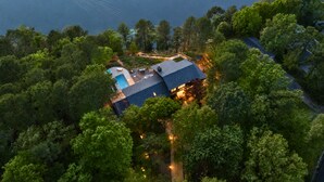 An aerial view of a house surrounded by dense trees, with a visible swimming pool and a dock extending into the water. - One Acre Private Oasis, Saltwater Pool, New Sauna, Outdoor Kitchen, and Fire Pit (Hot Springs)