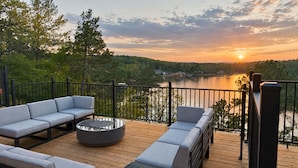 A deck with outdoor seating and a view of a lake at sunset. - One Acre Private Oasis, Saltwater Pool, New Sauna, Outdoor Kitchen, and Fire Pit (Hot Springs)