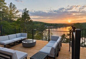 A deck with outdoor seating and a view of a lake at sunset. - One Acre Private Oasis, Saltwater Pool, New Sauna, Outdoor Kitchen, and Fire Pit (Hot Springs)