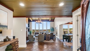A spacious living area with a wooden ceiling, stone flooring, and a view of the outdoors. - One Acre Private Oasis, Saltwater Pool, New Sauna, Outdoor Kitchen, and Fire Pit (Hot Springs)