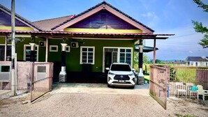 Uma casa de dois andares com telhado de telhas vermelhas, um caminho de acesso de pedras e um carro branco estacionado na frente.