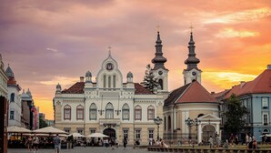 A historic building with a clock tower and a dome, surrounded by other buildings and a cobblestone square. - 1st Nest in Heart of Timisoara (Timisoara)